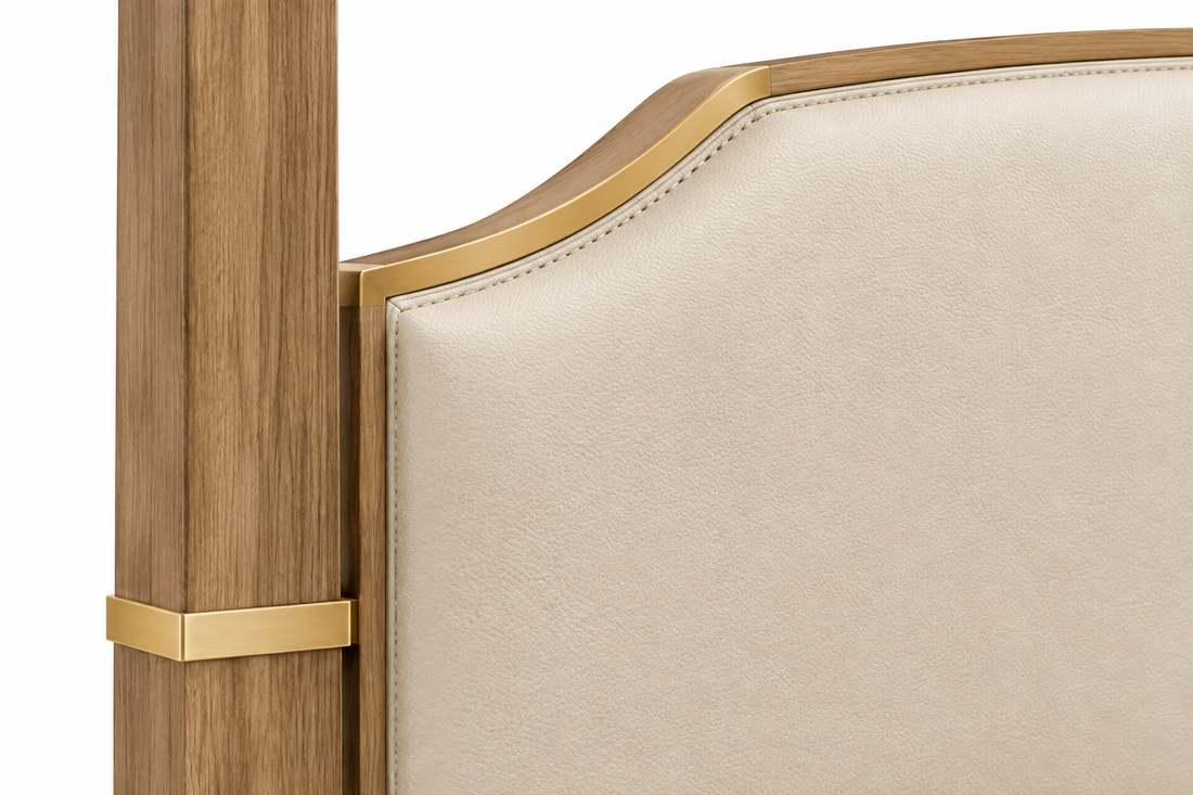 Close-up of the beige upholstered headboard, stitching, wood post, and gold-bronze trim