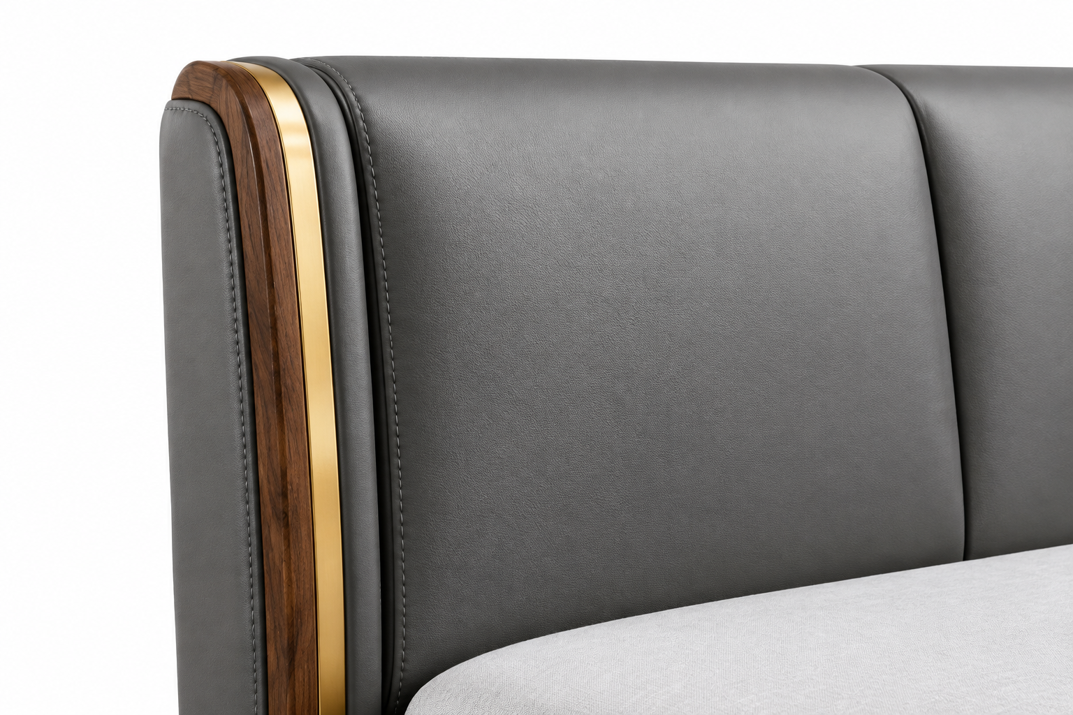 Close-up of gray leather upholstery, stitching, natural wood, and gold accent on the headboard