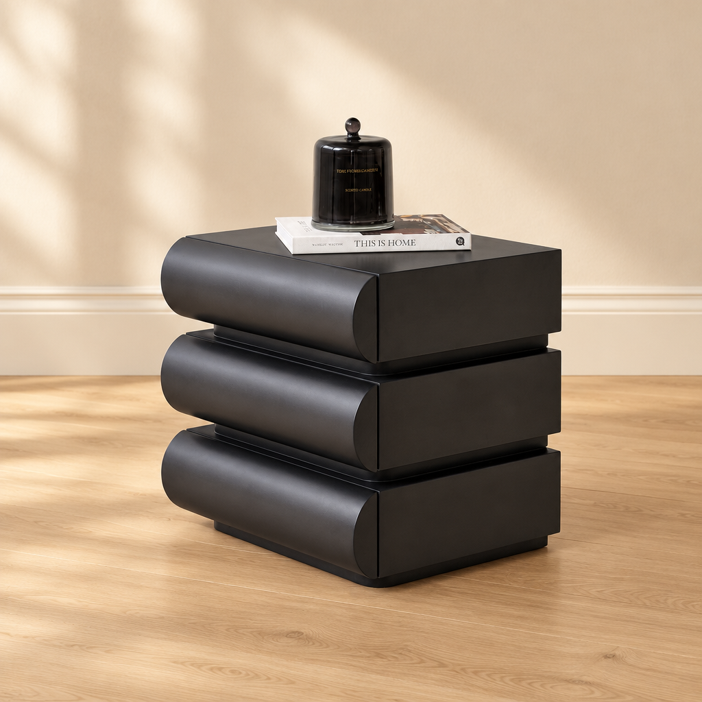 Angled view of Theo black bedside table on natural wood floor against warm beige wall